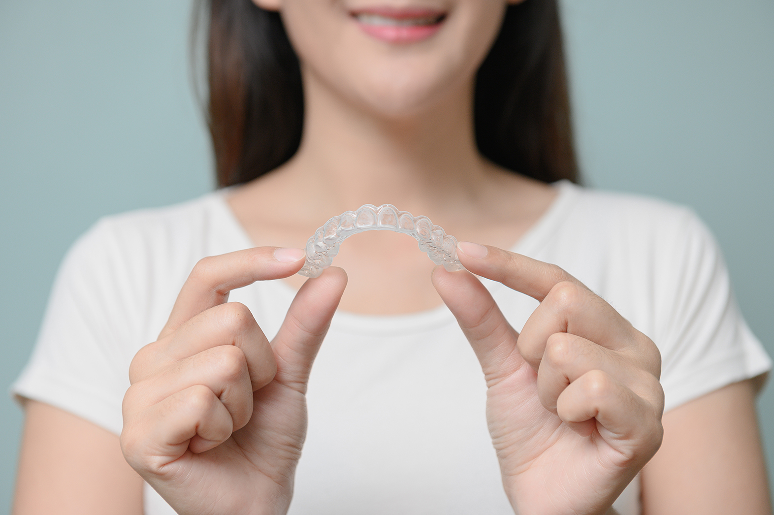 woman holding up invisalign treatment at the smile design